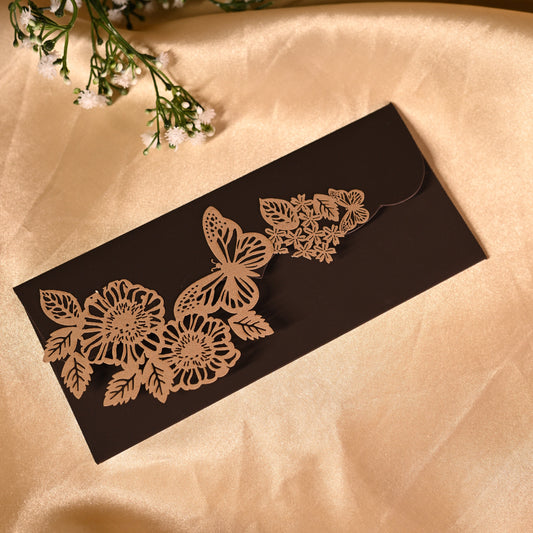 Decorative brown envelope with floral and butterfly patterns on a beige fabric background