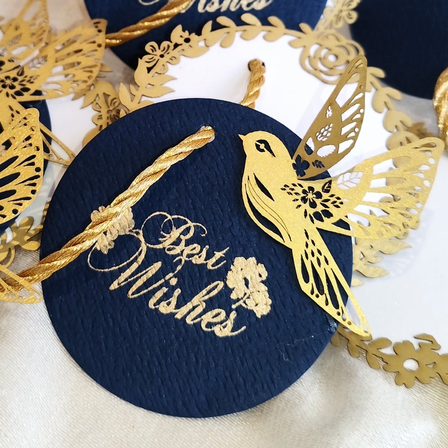 Layered blue gift tags with gold 'Best Wishes' text and gold bird cut-outs, in laser cut detailing