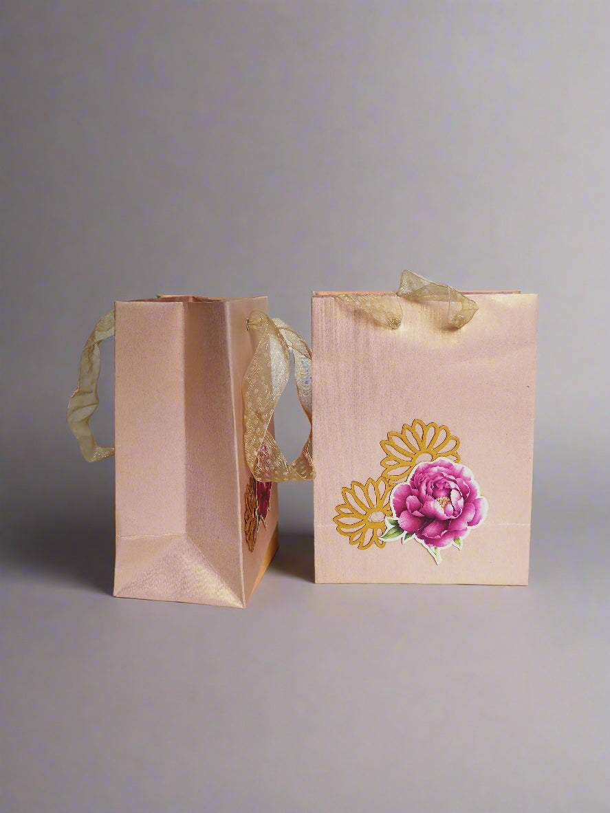 Two blush pink gift bags with floral designs