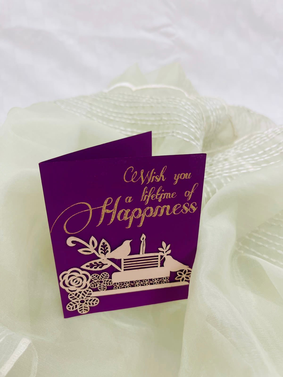 purple gift tag with intricate laser-cut detailing of birds, flowers and cake