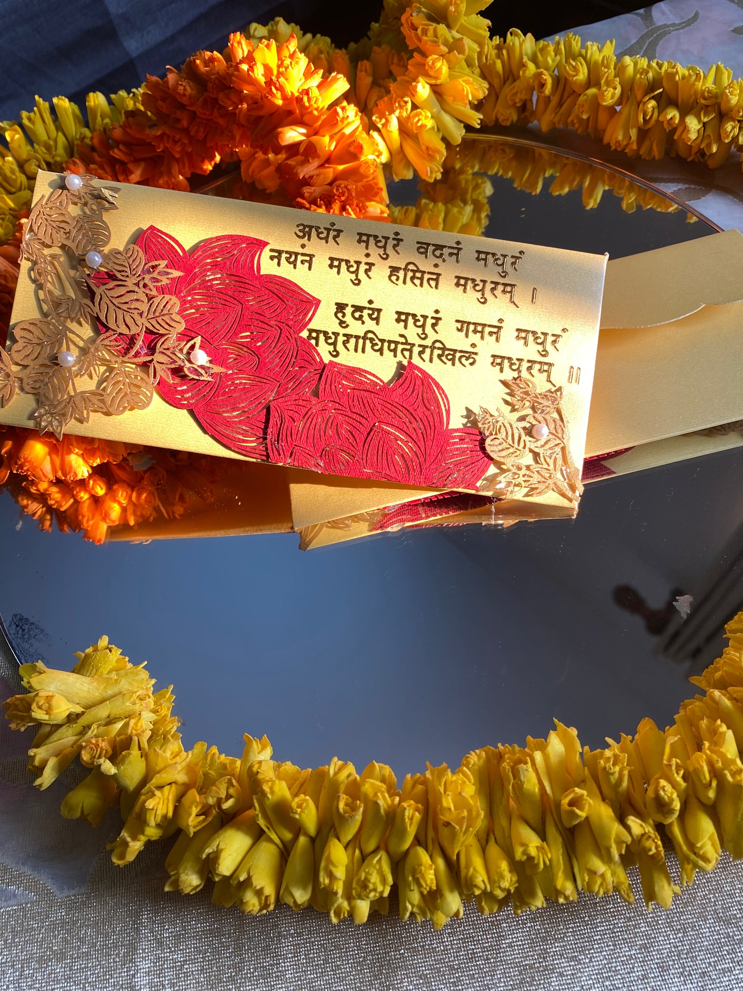 A decorative envelope with laser patchwork in green and gold colors, featuring floral designs and mantra in gold foil.
