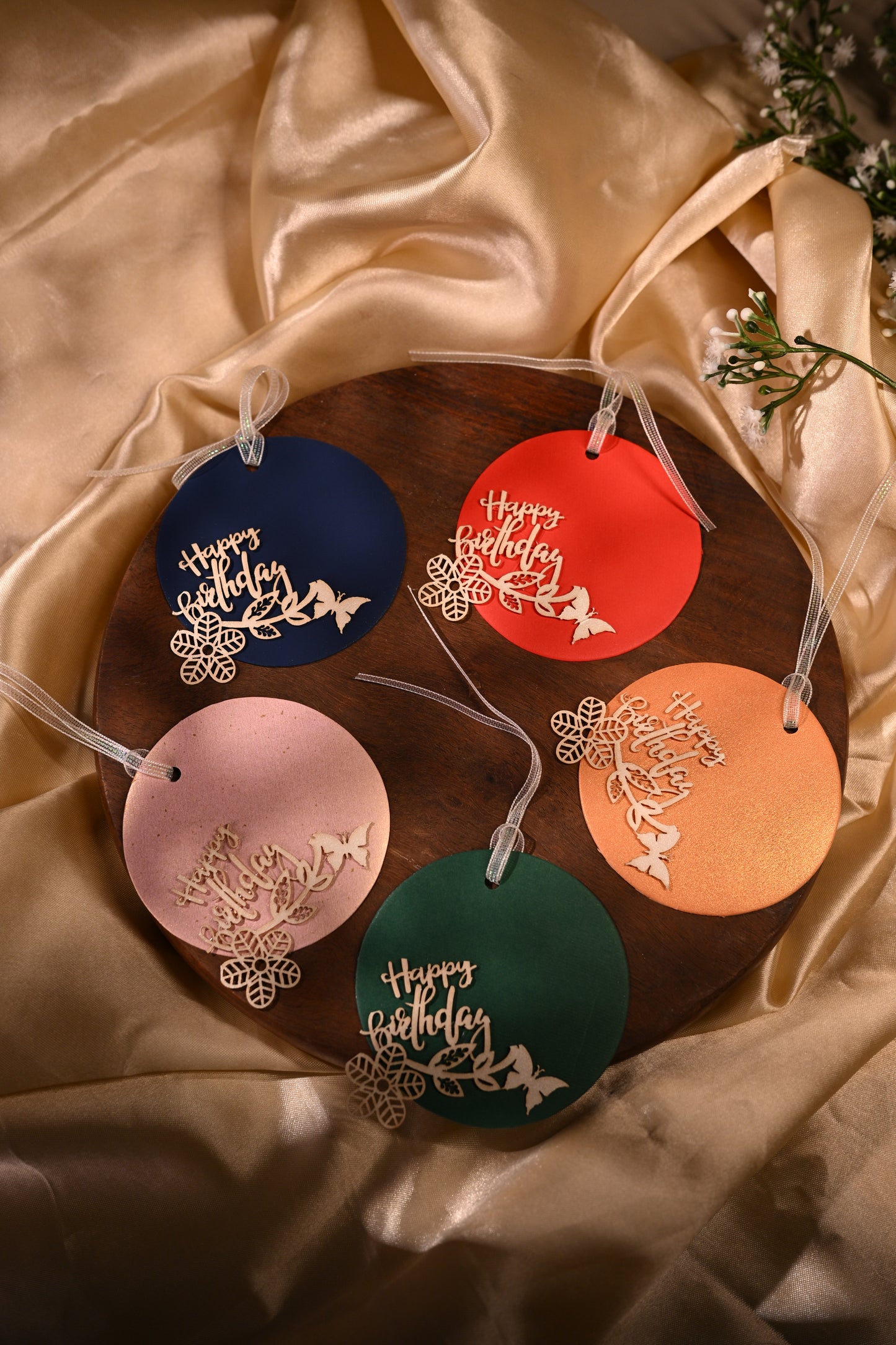 colourful round gft tags with the laser-cut message of happy birthday and punctured with a white ribbon