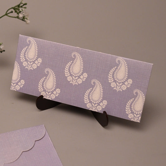 A lavender stationery set featuring a patterned envelope with white paisley motifs and a matching scalloped flap envelope, displayed on a neutral beige background with baby's breath flowers.