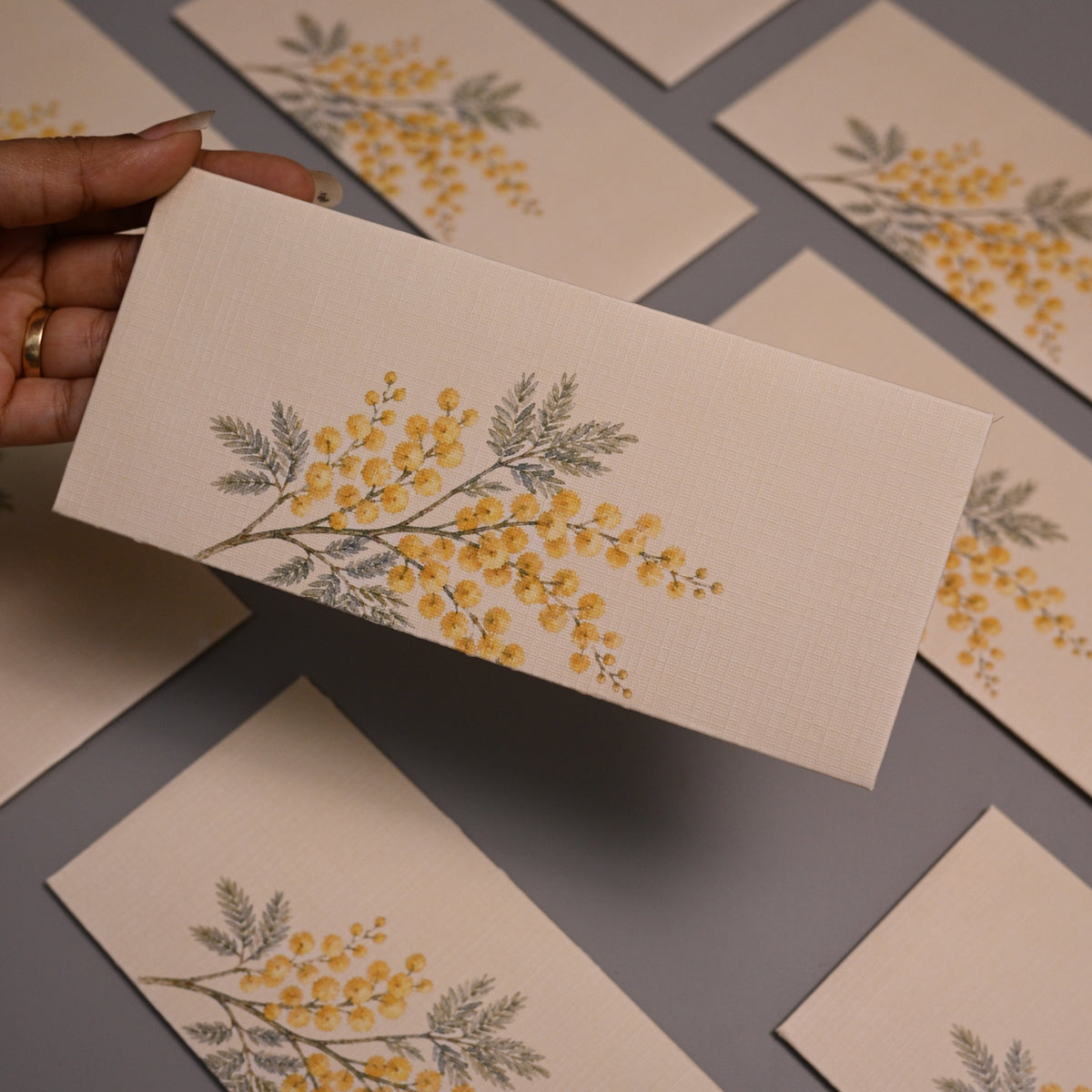 Envelope featuring a delicate yellow and gray botanical illustration of a flowering branch