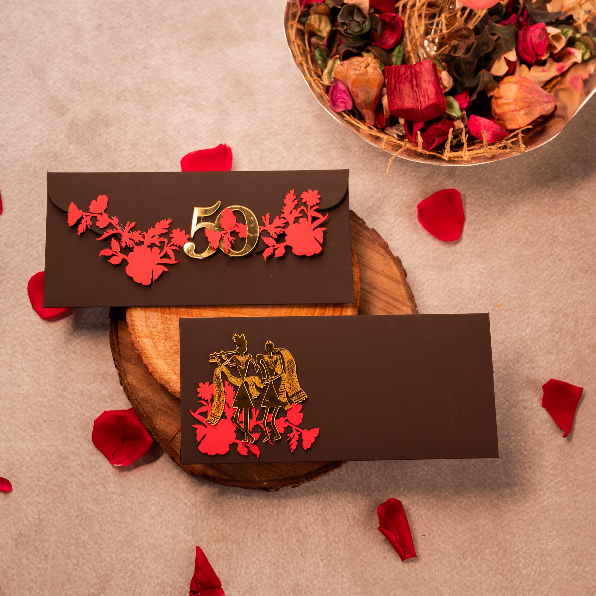 Decorative envelopes with floral designs and numbers on a textured surface with red petals.