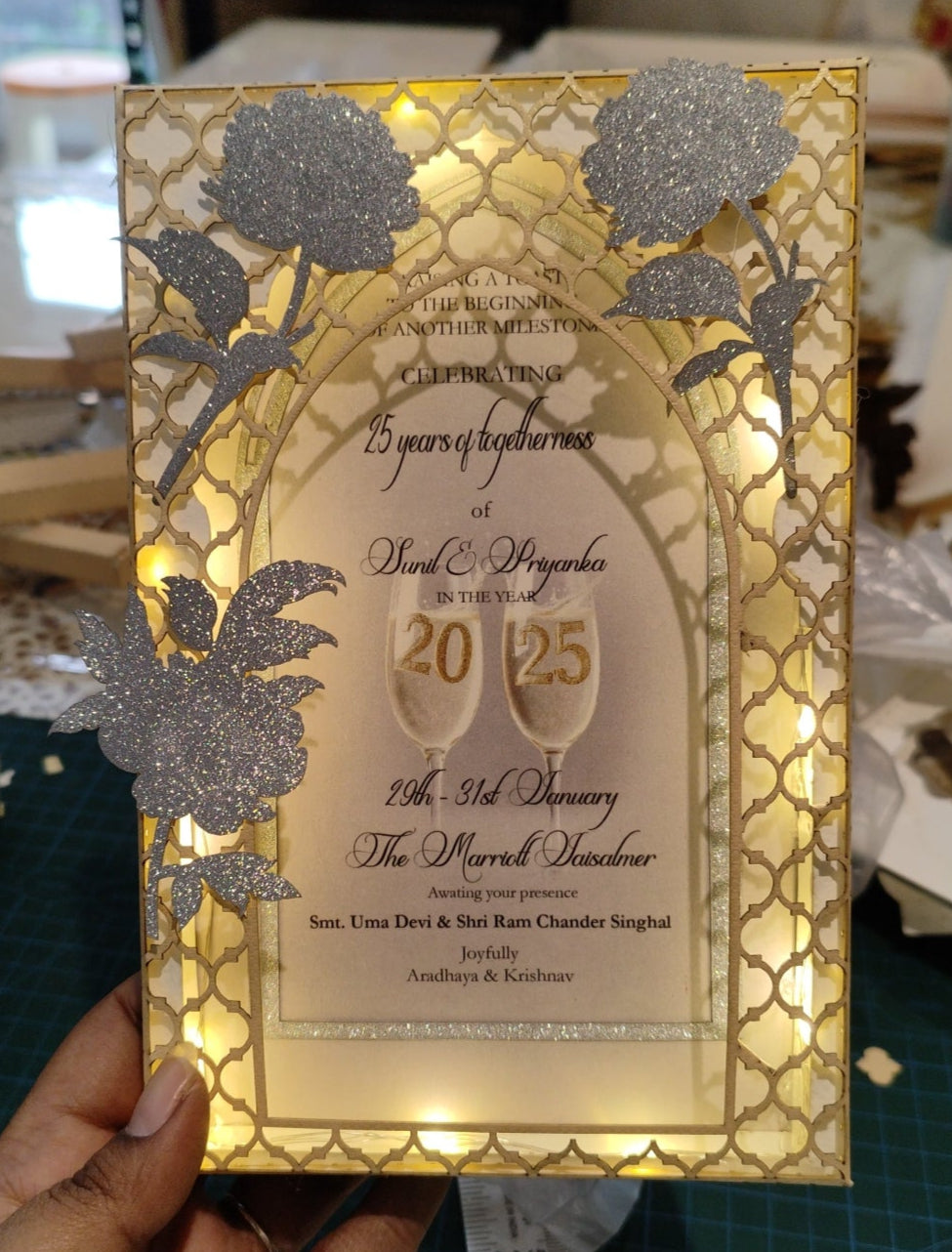 Decorative gold and silver invitation card with floral designs and text.
