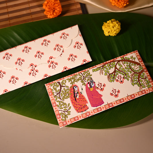 Decorative envelopes with floral designs on a green leaf, with a beige fabric and small flowers in the background