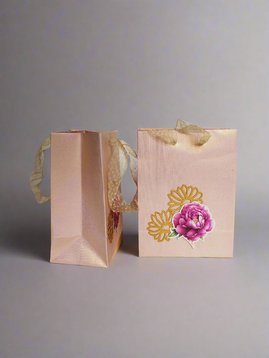 Two blush pink gift bags with floral designs 
