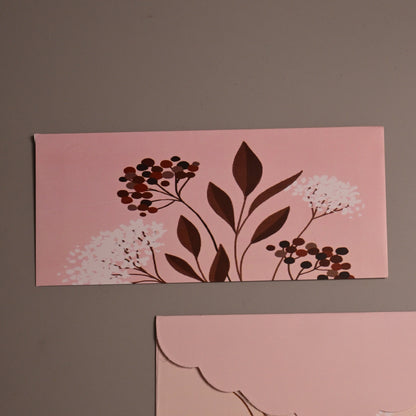 Two rectangular pink paper envelopes with brown leaf and berry illustrations, displayed on a plain taupe background.