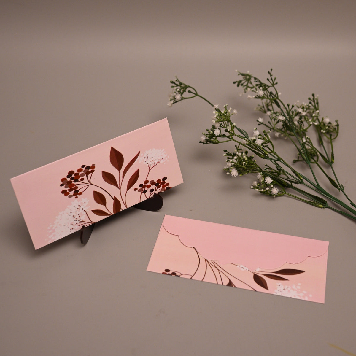 Envelope botanical illustrations, displayed on a neutral taupe background with baby's breath flowers.