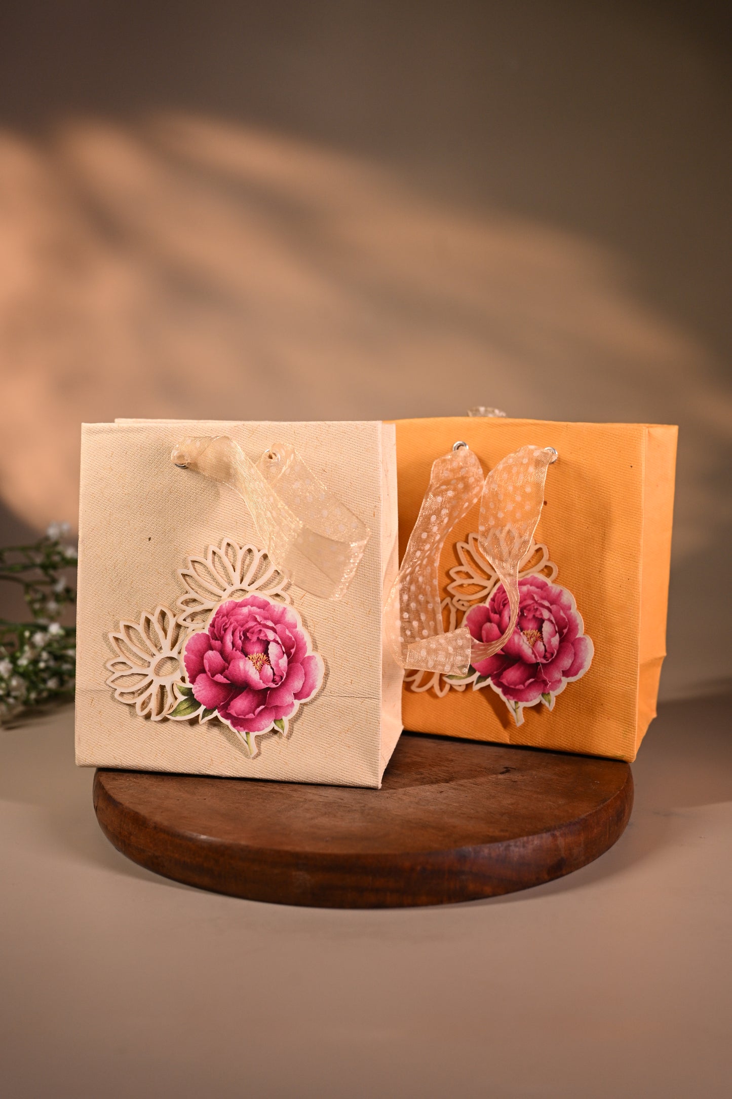 This is a pretty gift bag made from strong paper. It has a beautiful golden floral design with pink flower sticker on the front. The bag has gold ribbon handles, making it easy to carry and giving it a stylish touch.