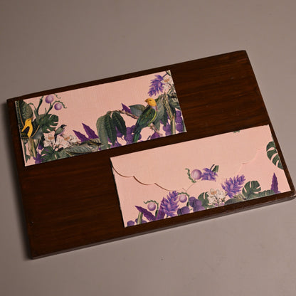 A rectangular dark brown wooden board with two decorative floral paper inserts, photographed on a plain taupe background.