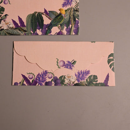 Two rectangular envelopes with a light pink background and a tropical floral and bird print