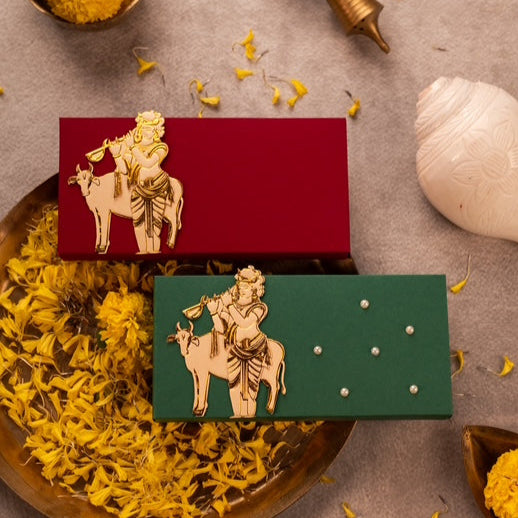 Cash Box, Gaddi Box krishana, Two embossed cash box, envelopes with deities lord Krishana, one is red with a gold-foiled figure of a Krishana and cow, and the other is green with a similar design.