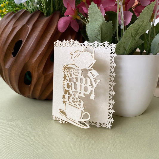 Decorative white gift tags with laser-cutwork, featuring a teapot, teacup and saucer, writing