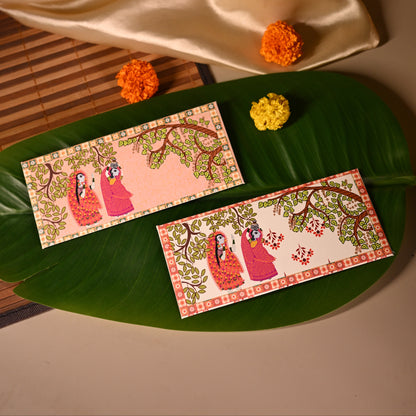 Decorative envelopes with floral designs on a green leaf, with a beige fabric and small flowers in the background