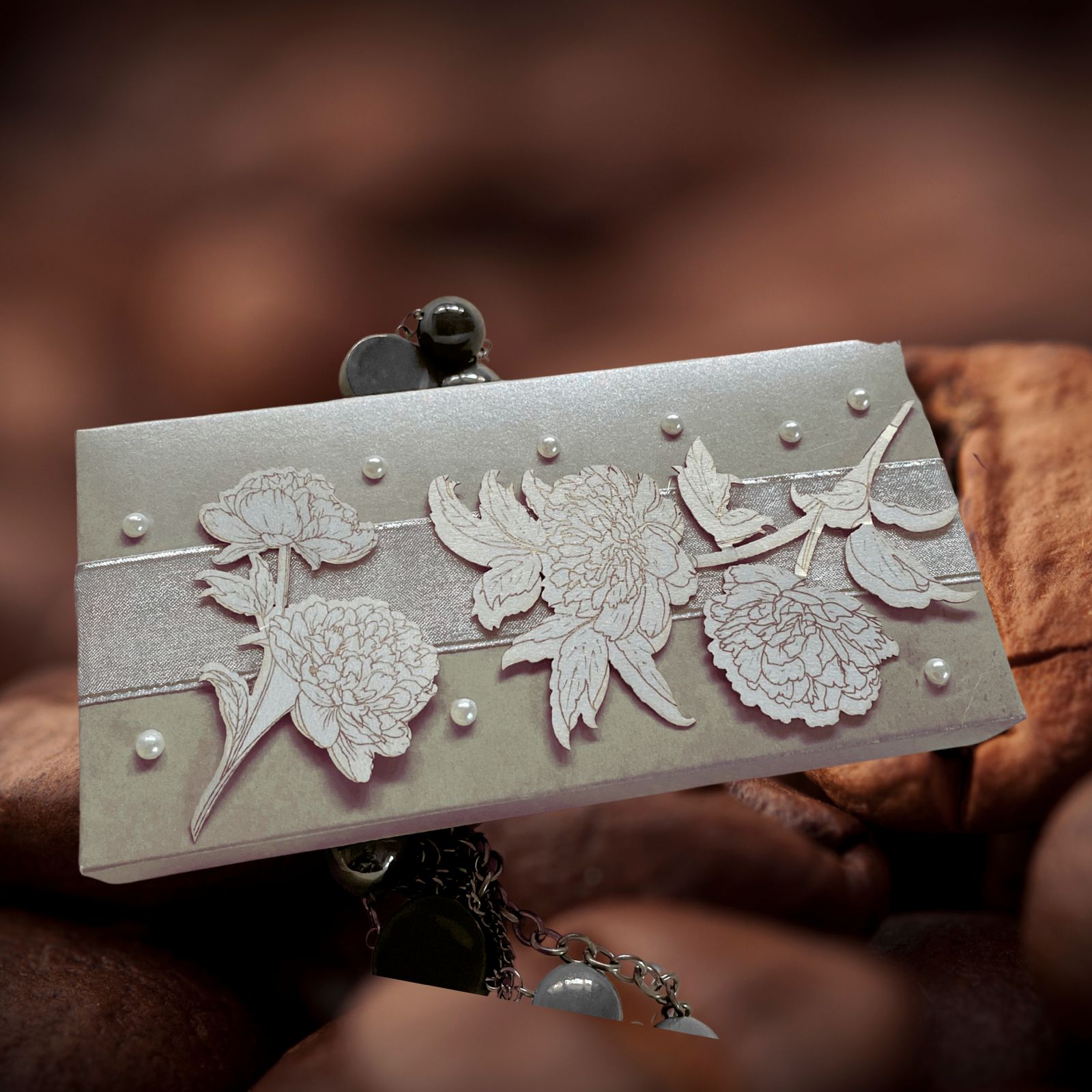 silver cash box with a white ribbon in the middle with flower cutouts and pearls