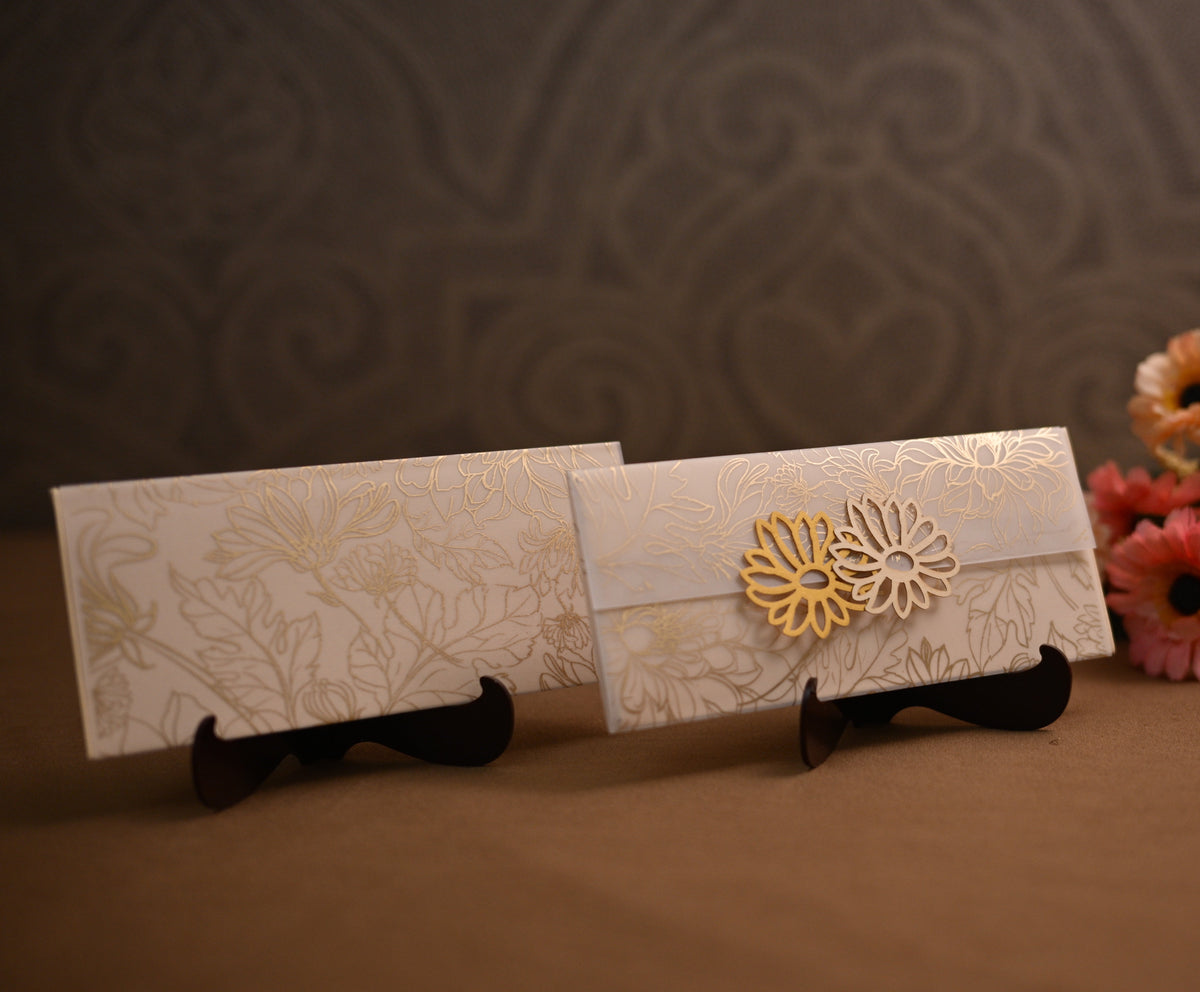 Two white embossed paper envelopes with gold floral patterns 
