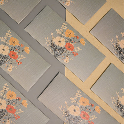 Envelopes arranged diagonally on a gray surface, each printed with a floral bouquet design in orange, cream, and yellow tones.