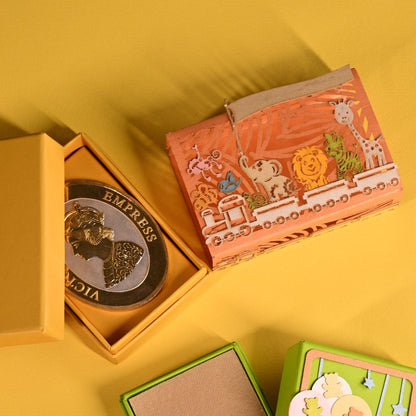 3 colorful decorative boxes, some open and some closed, arranged on a solid yellow background. The boxes feature various illustrations, patterns, and colors including orange, green, blue, purple, and beige.