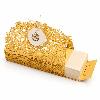 A decorative yellow box with intricate cutout detailing with a small round tag attached. The box is open slightly, revealing a light beige interior or insert, 