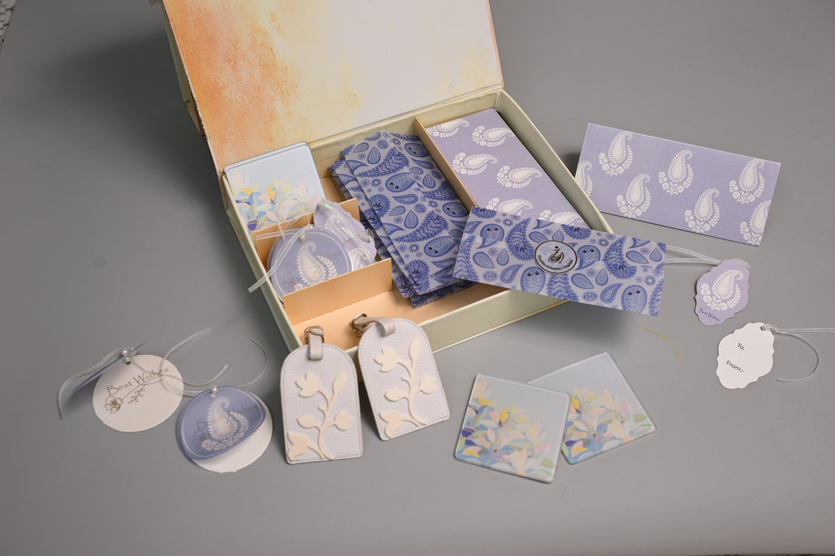 A gift set of coaster and tags with blue paisley and floral patterns envelopes, displayed in an beige box 