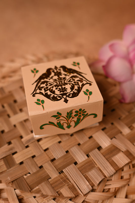 A beige cardboard coin box with a foil embossed parrot motif