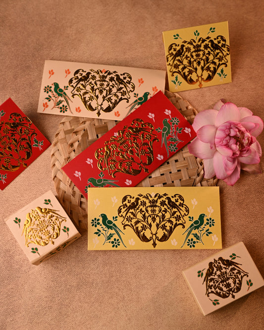 Decorative shagun envelopes with traditional gold parrot designs on a textured surface