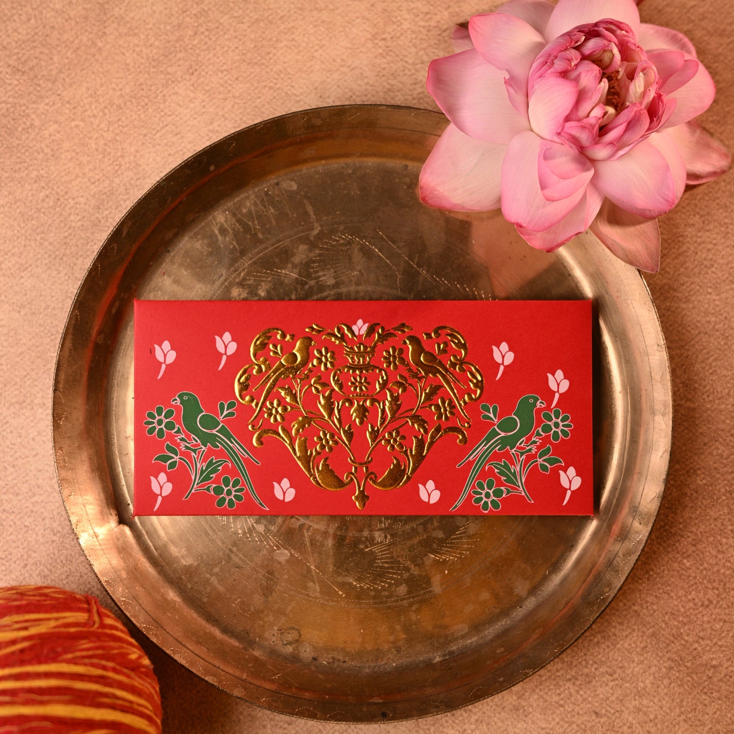Decorative shagun envelopes with traditional gold parrot designs on a textured surface