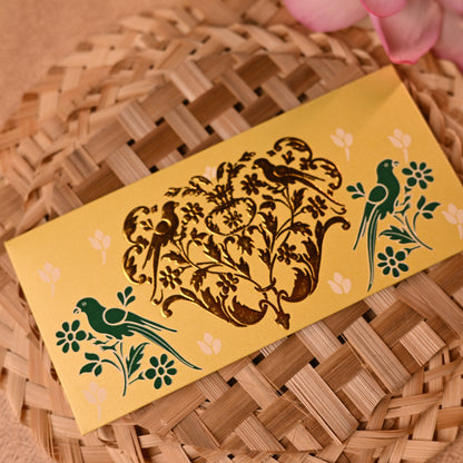 Decorative shagun envelopes with traditional gold parrot designs on a textured surface