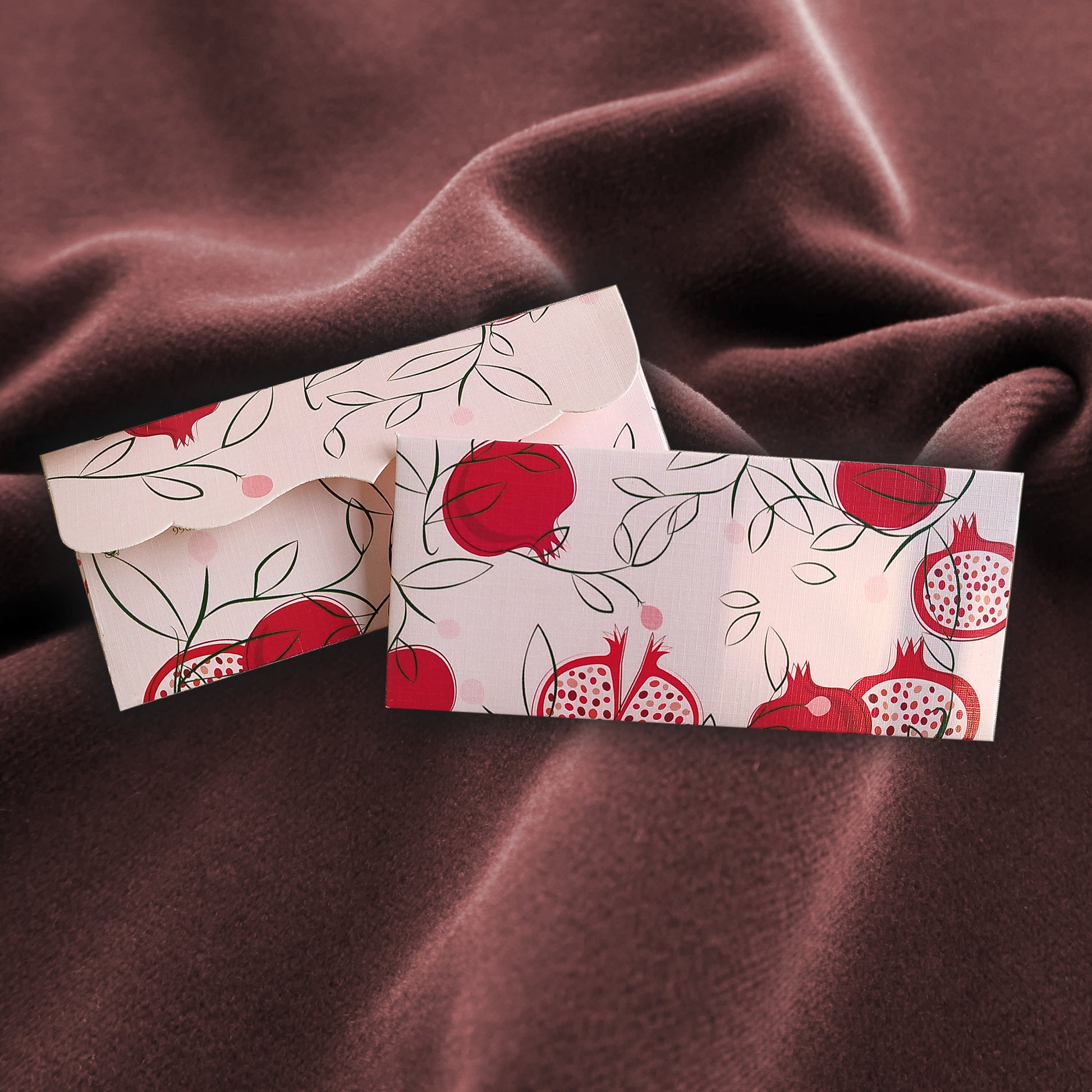 Two light envelopes with red pomogrenate designs