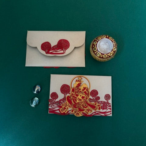 A set of laser-cut money envelopes with a Radha Krishna motif, in red, gold, and silver colours