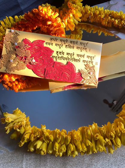 A decorative envelope with laser patchwork in green and gold colors, featuring floral designs and mantra in gold foil. 
