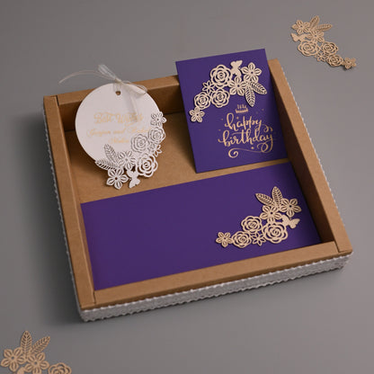 A luxury stationery set for a birthday celebration, featuring a kraft paper box with a purple card, a matching round tag, and gold laser-cut floral accents on a gray background.