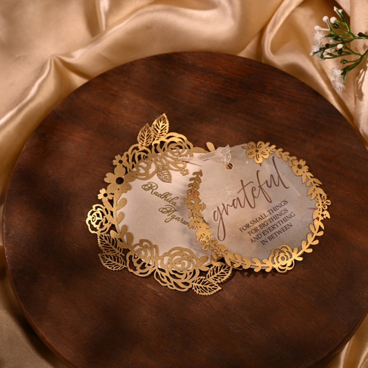 Two elegant laser-cut wedding invitation cards with gold floral borders and white centers