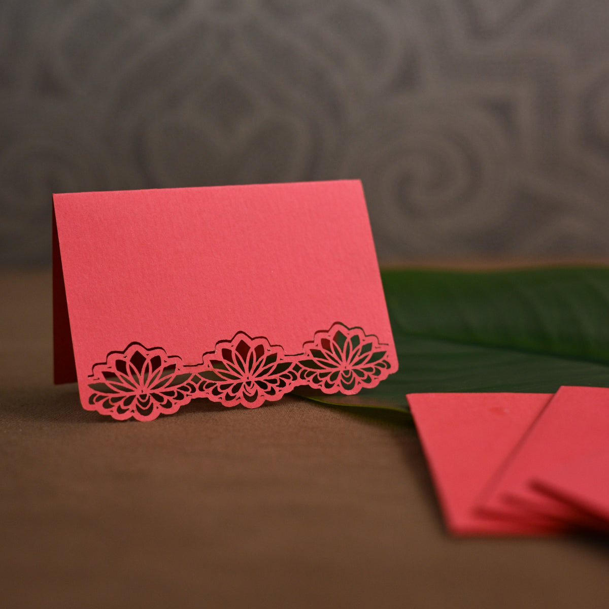 A coral pink gift tag with laser-cut floral lace border along the bottom.