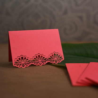 A coral pink gift tag with laser-cut floral lace border along the bottom.