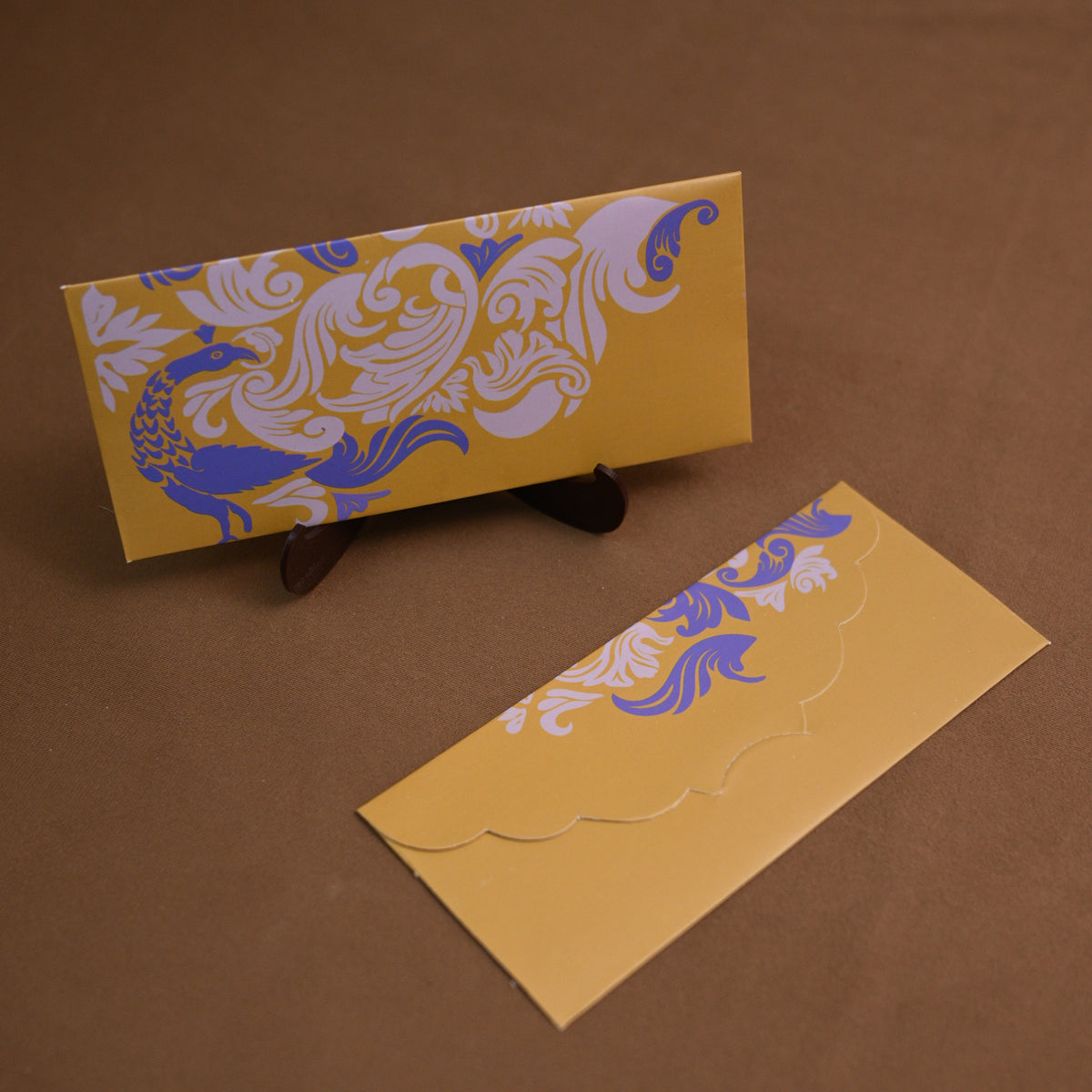 A yellow peacock envelope with a blue and white  floral and blue peacock.