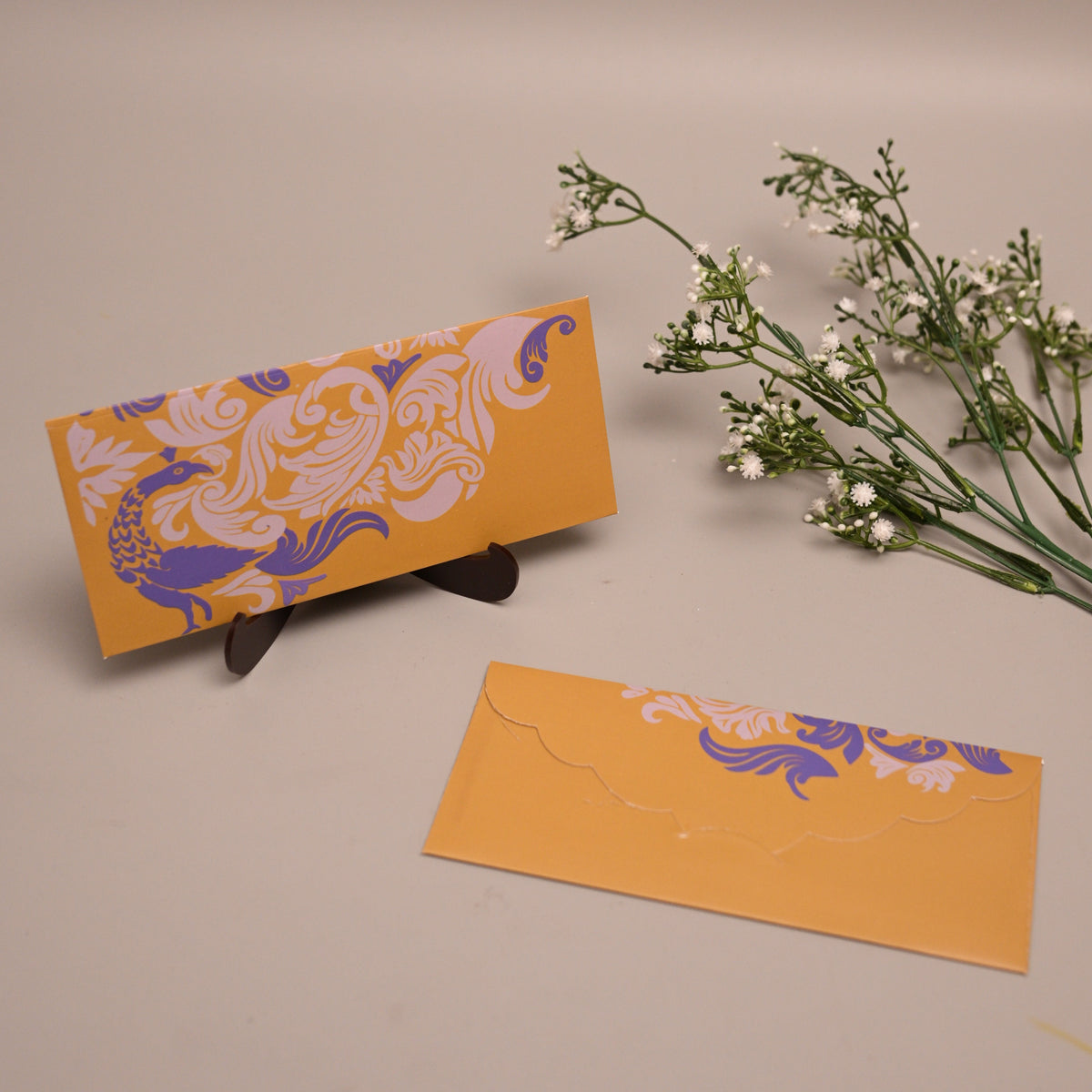 A pair of Mendhi yellow envelopes with purple and white ornate floral patterns