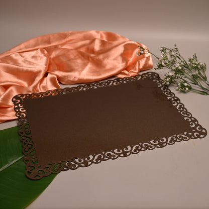 A dark brown rectangular placemat with an ornate laser-cut scalloped border 