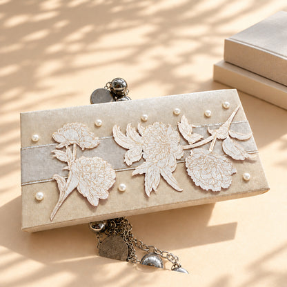 silver cash box with a white ribbon in the middle with flower cutouts and pearls