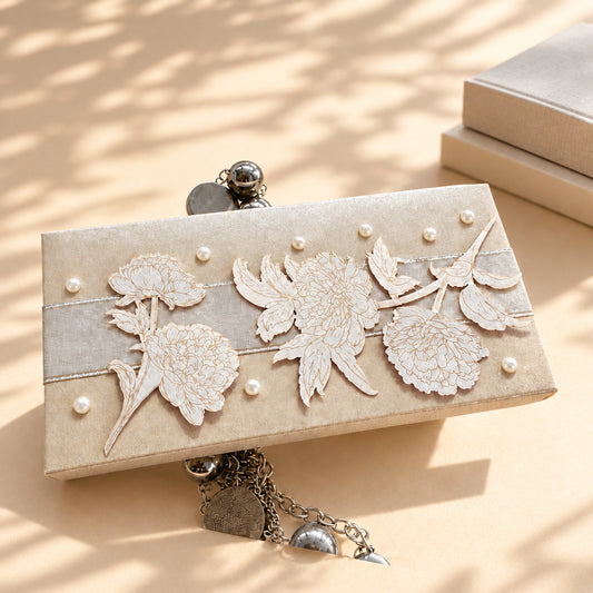 silver cash box with a white ribbon in the middle with flower cutouts and pearls