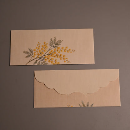 beige envelopes with scalloped edges, one featuring a yellow floral branch 