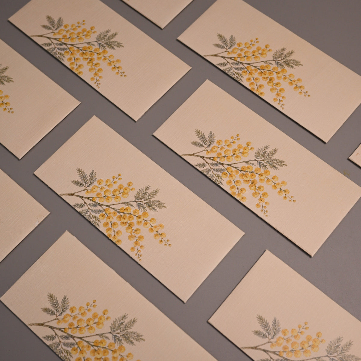 A set of rectangular cream-colored envelopes, each printed with a delicate yellow and green floral branch motif.