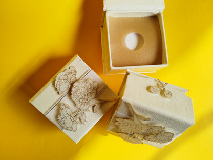 White coin box with gold print white flower