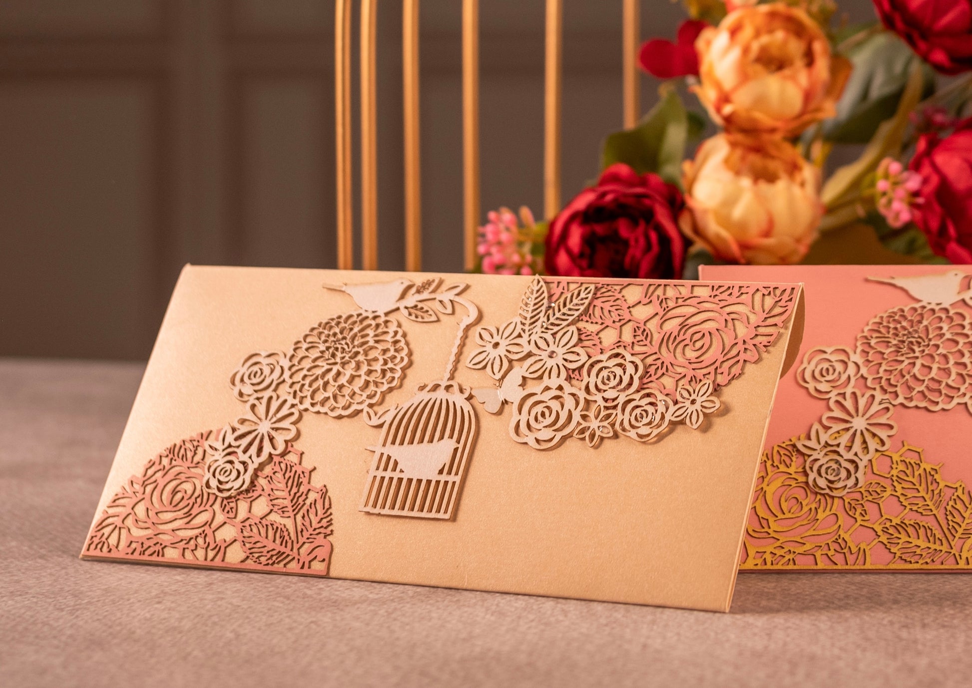 Off-white envelope featuring intricate laser-cut design of flower motifs, birds and cages