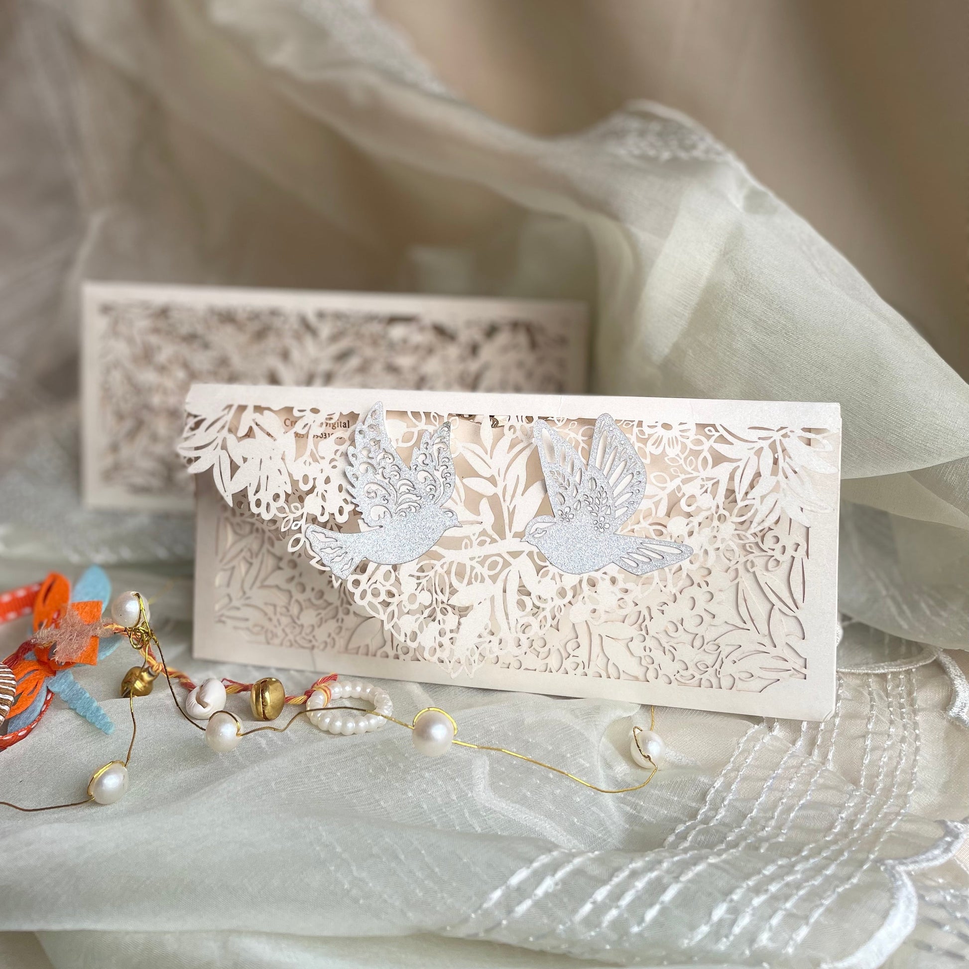 white colour envelope with full laser-cut box and floral detailing and two birds on the flap
