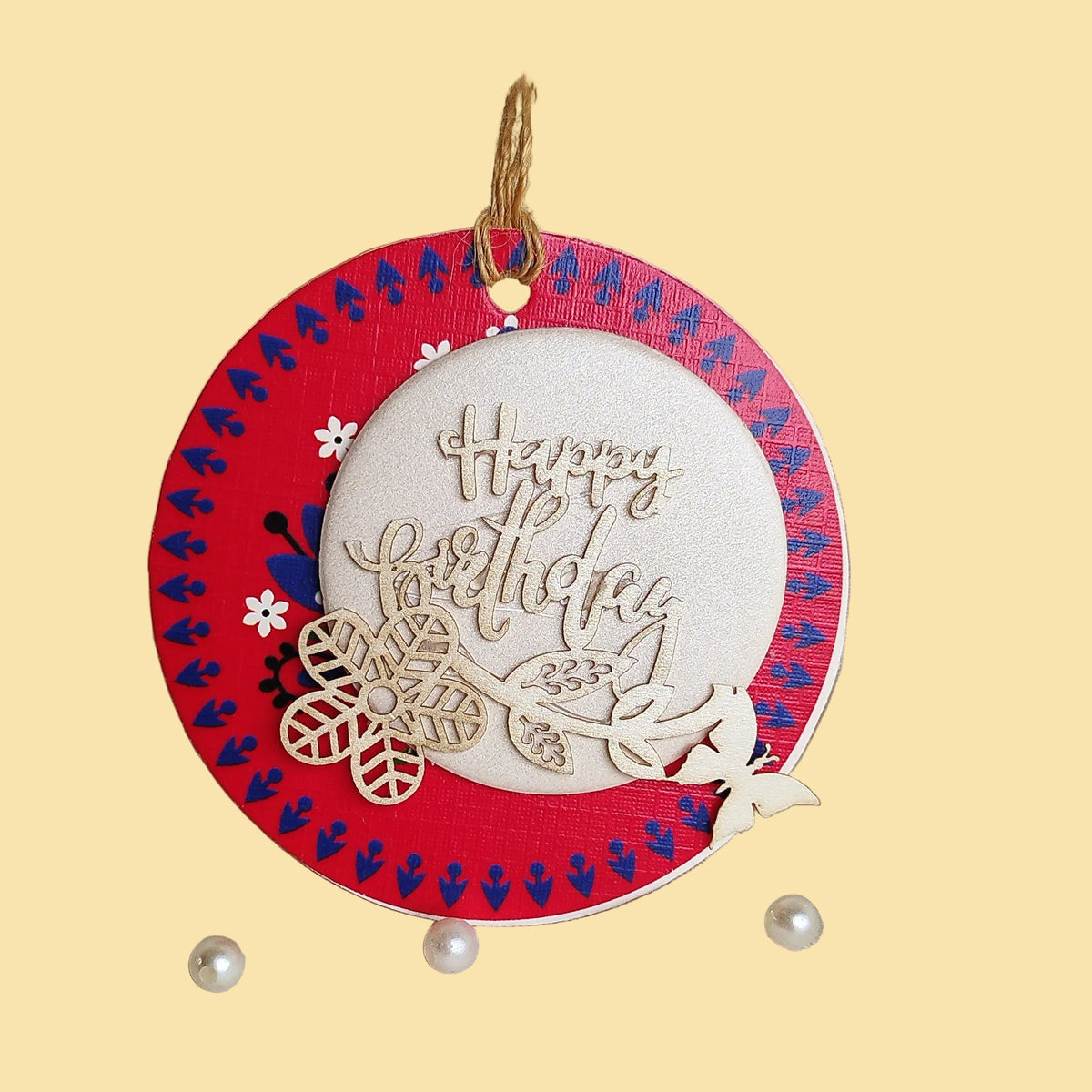 A gift tag with a three-layer design, decorated with laser-cut flowers and butterflies, hanging from a string.