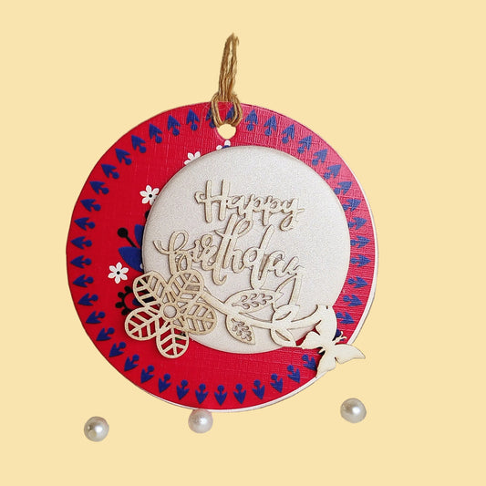 A gift tag with a three-layer design, decorated with laser-cut flowers and butterflies, hanging from a string.