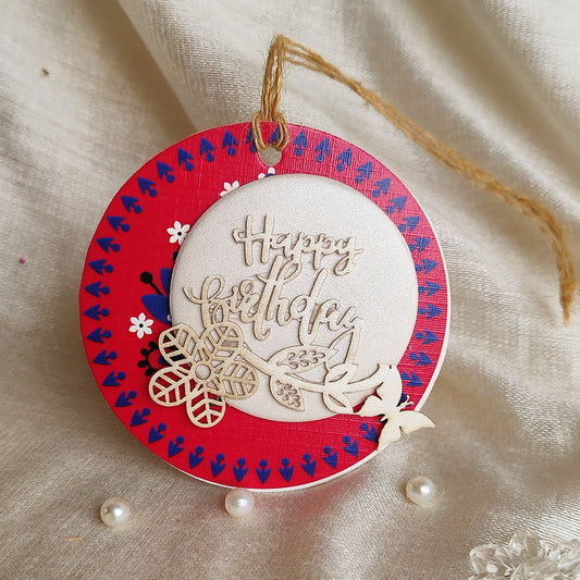 A gift tag with a three-layer design, decorated with laser-cut flowers and butterflies, hanging from a string.